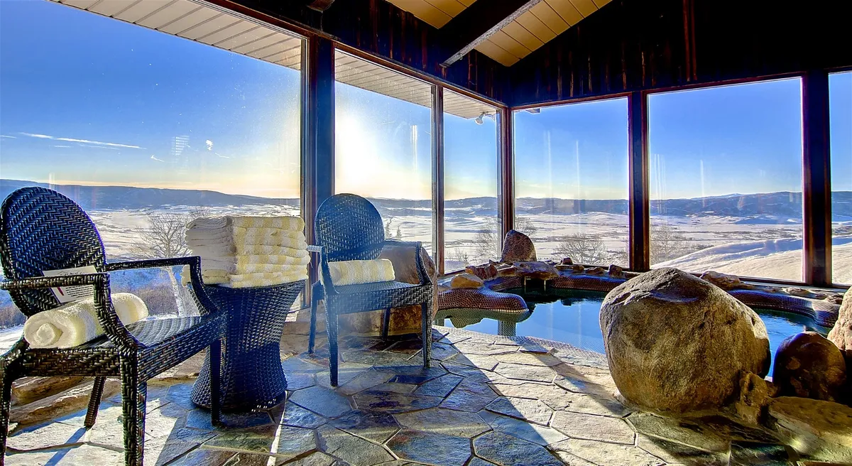 A peaceful spa area with a focus on natural stone accents, crisp towel arrangements, and large windows that frame mountain views. The room exudes a sense of luxury and organized relaxation, perfect for unwinding after outdoor adventures.