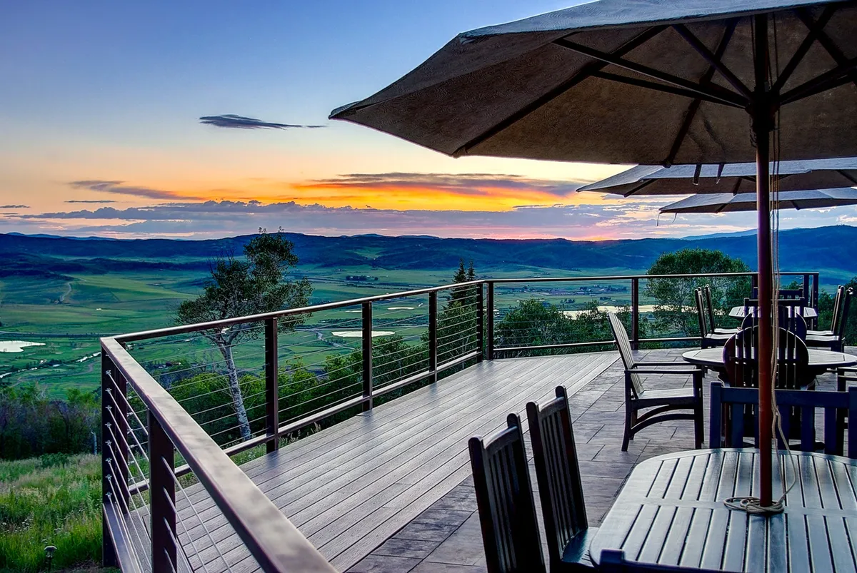 A deck with comfortable patio furniture overlooking a majestic mountainous landscape and a brilliant sunset sky. The space is perfect for outdoor meetings, group dinners, or simply taking in the inspiring views as a team.